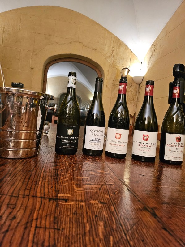 Sticle de vin Château Mont-Redon pregătite pentru degustare într-o pivniță
